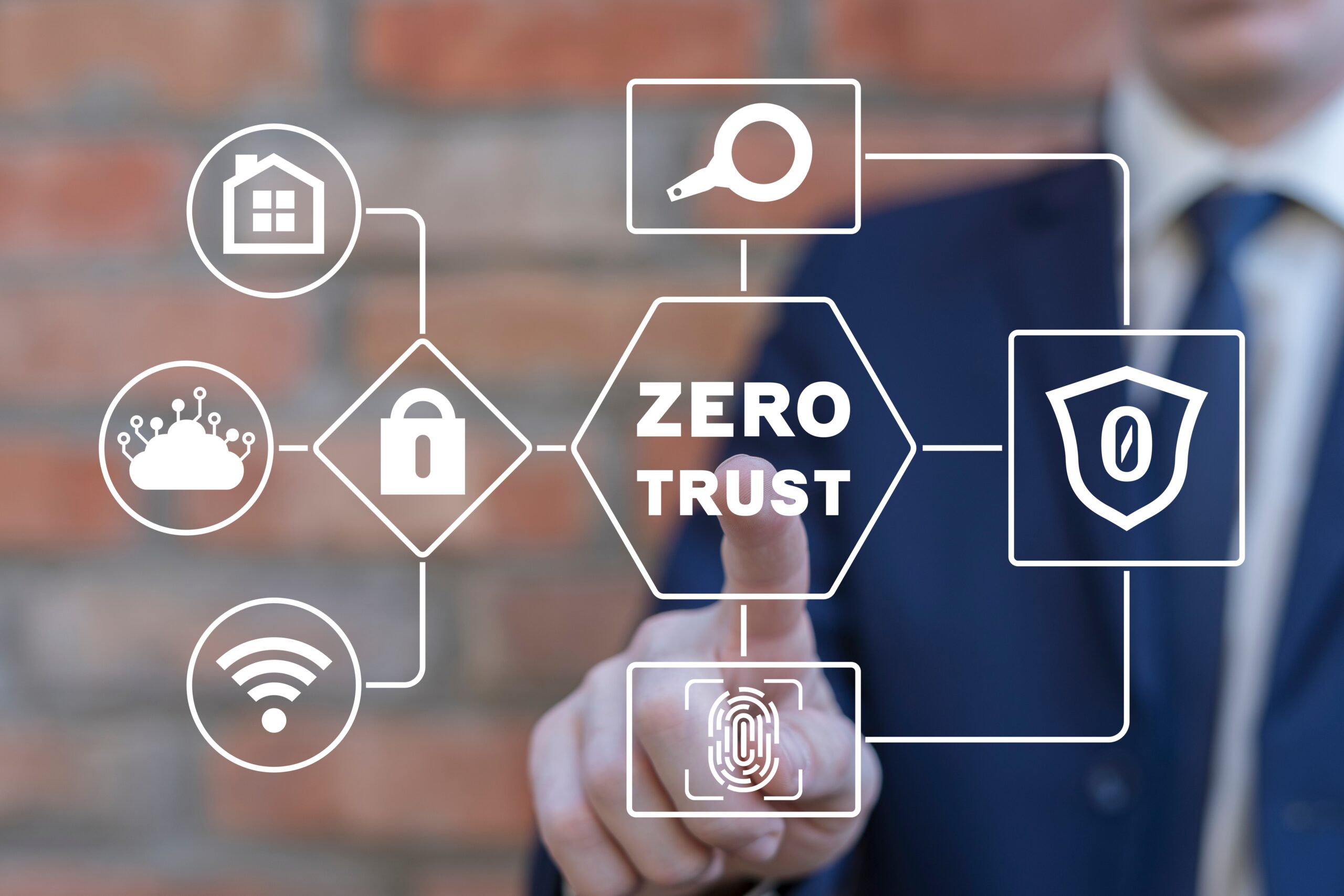 In the foreground, the words Zero Trust are surrounded by icons representing wifi, locks, networks, a home, etc. In the background, a white businessman reaches out to touch the words Zero Trust.